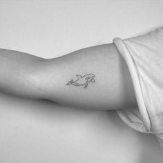 a woman's arm with a small dolphin tattoo on the left side of her arm