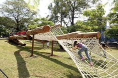 two children playing in a hammock made from logs and roped with ropes