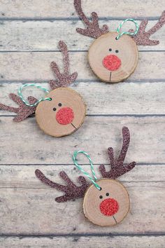 three reindeer ornaments made out of wood slices on a wooden table with string attached to them