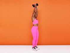 a woman in pink workout clothes lifting two dumbbells over her head with an orange background