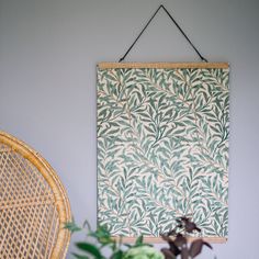 a green and white wall hanging next to a wicker chair