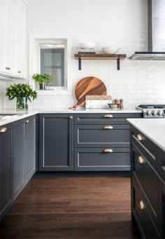 a kitchen with gray cabinets and white counter tops, wooden cutting board on the wall