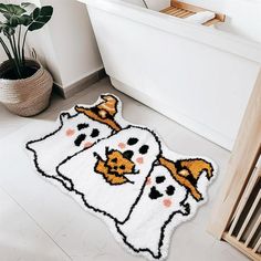 two white rugs with black and orange cats on them in front of a bathtub