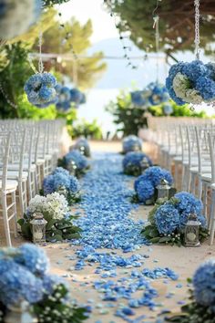 an aisle with blue flowers and white chairs