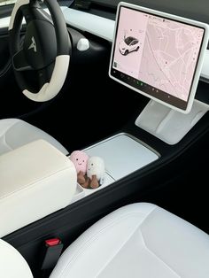 a car dashboard with a monitor and stuffed animals in the center console, along with steering wheel controls