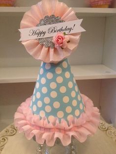 a blue and white polka dot birthday hat with a pink rose on top that says happy birthday