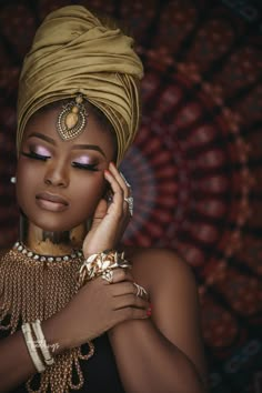 a woman in a turban with jewelry on her head and hands near her face