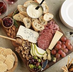 an assortment of cheeses, meats and crackers on a wooden platter