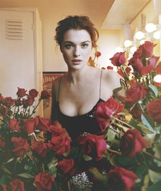 a woman in a black dress is surrounded by red roses