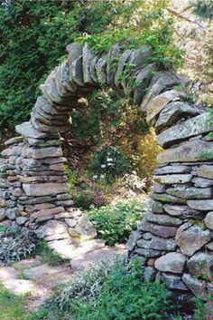 a stone arch in the middle of a garden