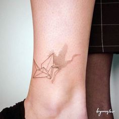 a woman's foot with a small origami bird tattoo on it