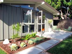 a house with some plants in front of it and a patio area next to it