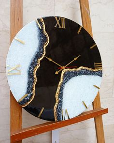 a clock that has been made to look like an abstract piece of art with gold and black paint