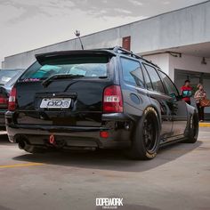 the back end of a black car parked in a parking lot