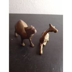 two small figurines of animals on a black table top with white wall in the background