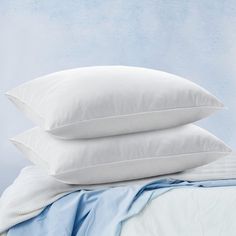 three pillows stacked on top of each other next to a blue blanket and pillow case