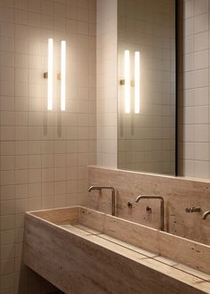 a bathroom sink with two mirrors above it and lights on the wall next to it