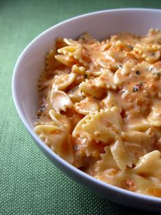 a white bowl filled with macaroni and cheese on top of a green table