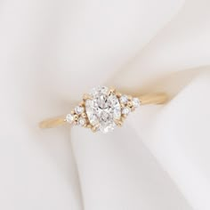 a diamond ring on top of a white cloth with gold accents and diamonds in the center