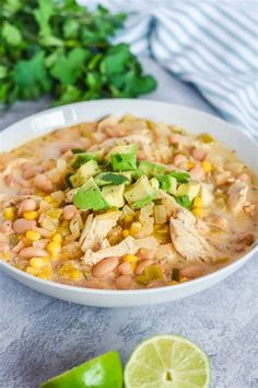 a white bowl filled with chicken, beans and avocado on top of a table