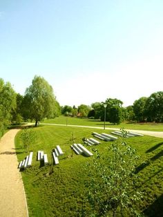 there are many benches on the grass by the path in front of the park area