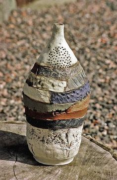 a white vase sitting on top of a wooden table next to gravel and rocks in the background