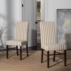 two striped chairs sitting next to each other in front of a painting on the wall