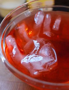 a glass filled with ice sitting on top of a wooden table