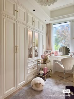 a bedroom with white furniture and chandelier hanging from it's ceiling, next to a large window