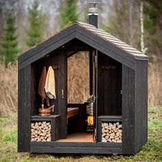 an outhouse with logs in the front and door open to show it's interior