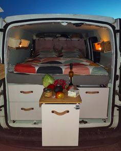 the bed in the back of a van is neatly packed with food and drinks on it