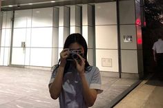 a woman taking a photo in front of a building with her camera up to her face