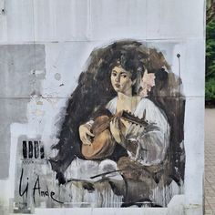 a mural on the side of a building depicts a woman playing a guitar and holding a book