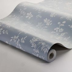 a blue and white wallpaper with floral designs on the side, it's rolled up