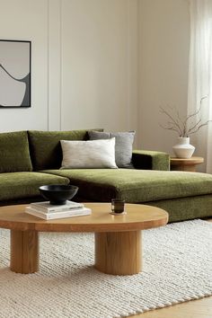 a living room with a green couch and coffee table in front of a white wall