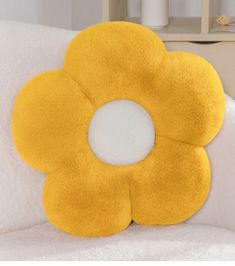 a yellow flower shaped pillow sitting on top of a bed