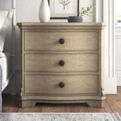 a white vase sitting on top of a wooden dresser next to a bed in a room