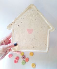 a hand holding a small ceramic house shaped dish