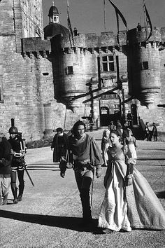 a man and woman walking in front of a castle