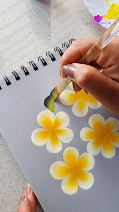 a person is painting flowers on a notebook