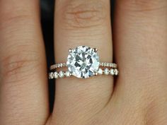 a woman's hand with a diamond ring on top of her finger and the engagement band