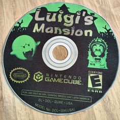 a cd disc that is sitting on a wooden floor with the words luigi's mansion printed on it