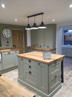 a kitchen with an island and wooden floors in front of a clock on the wall