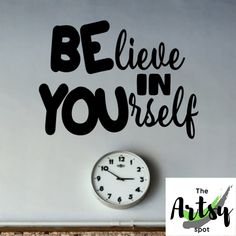 a clock sitting next to a wall with the words believe in yourself on it