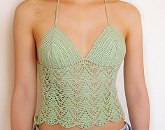 a woman wearing a green crochet top and denim shorts with her hair pulled back