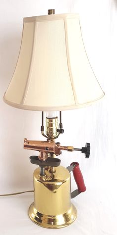 "For sale is a fascinating and unique electric lamp with industrial appeal made from shiny solid brass, cast iron, and copper welding blow torch. Circa 1910-20's. Handcrafted lamp was put together by a Math High School teacher who started his hobby in the late'70's. His goal was to create useful items out of reused and recycled materials. The welding blow torch lamp features a polished brass body with red painted wooden handle, a moving piston hand pump, cast iron holder, hard rubber valve, copp Pipe Lights, Copper Welding, Recycled Lamp, Antique Lights, Car Parts Decor, Electric Desk, Repurposed Lamp, Blow Torch, Torch Lamp