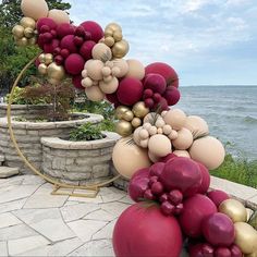 a bunch of balloons that are in the air near some rocks and water with trees