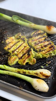 the grill has asparagus on it and some meat is being grilled over