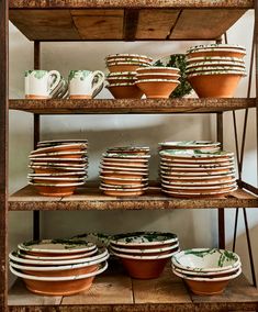 a shelf filled with lots of plates and bowls on top of wooden shelves next to each other