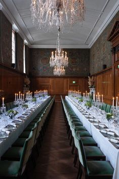 the long table is set up with many place settings and candles on each one side